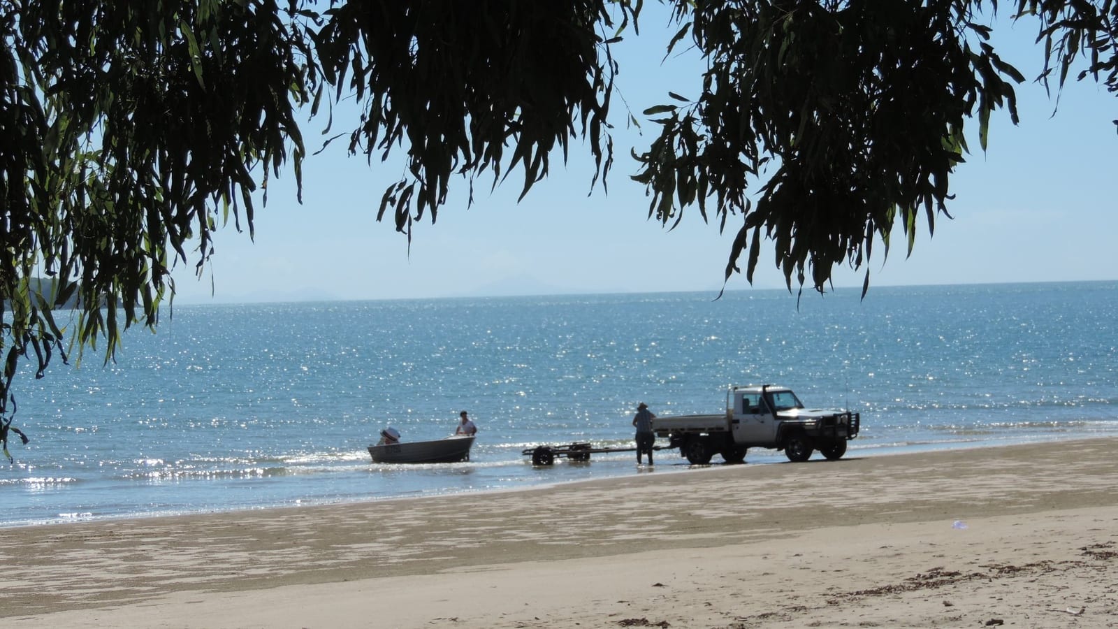 A small boat being launched from the beach at Shoal Point, with Green Island beyond